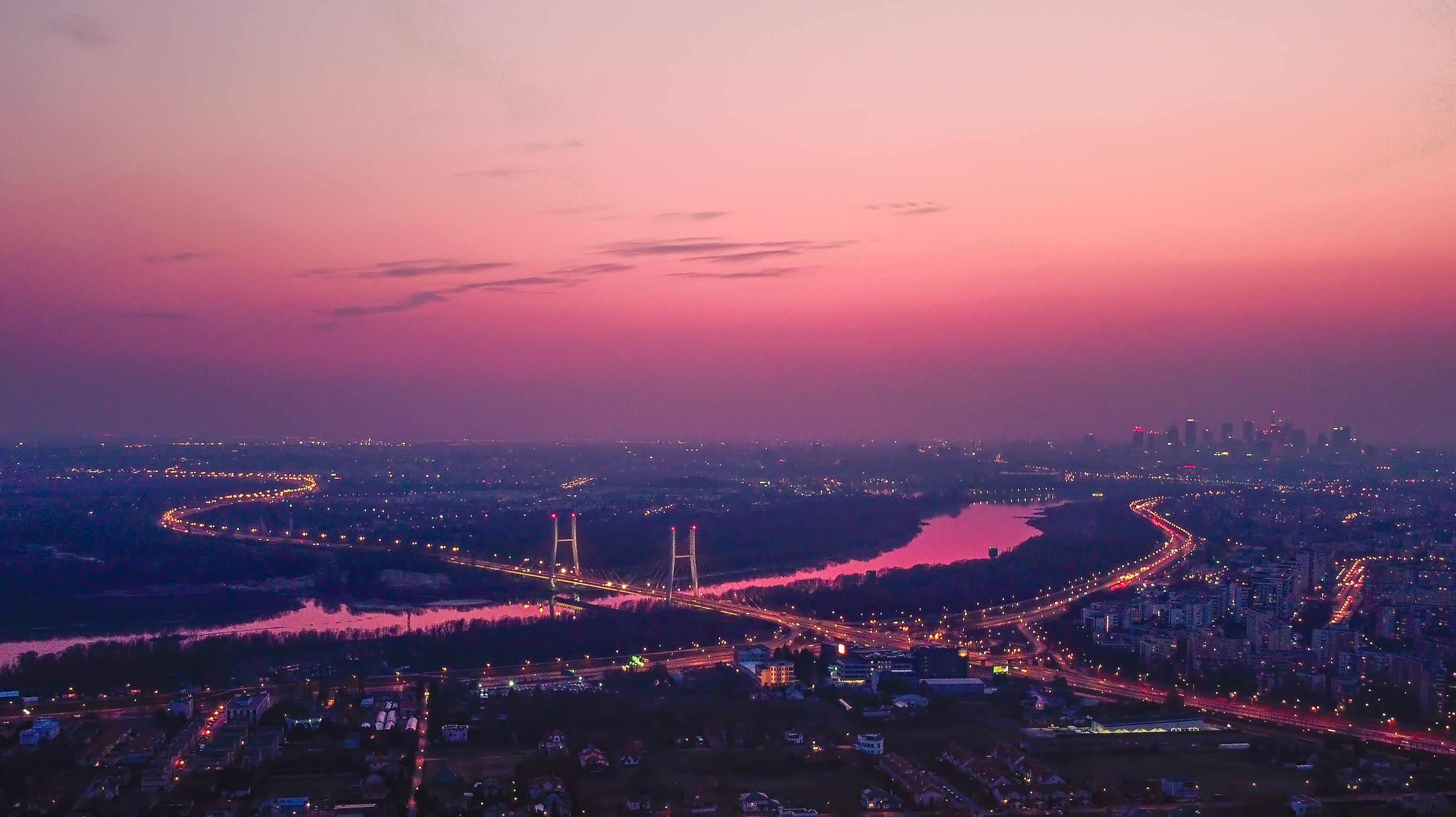 city skyline during dusk, with pink light glowing over a river