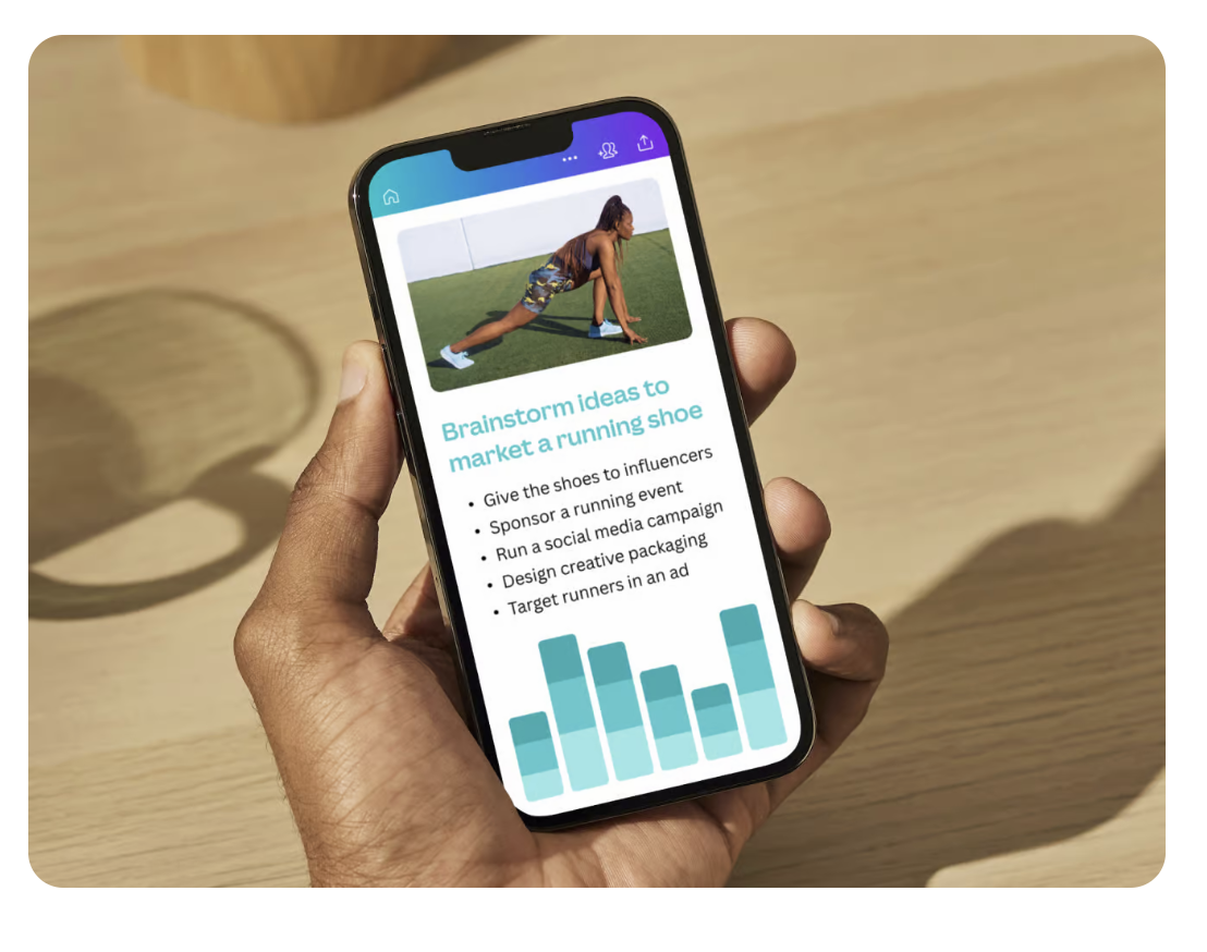 A hand holding a smartphone showing Canva's website.