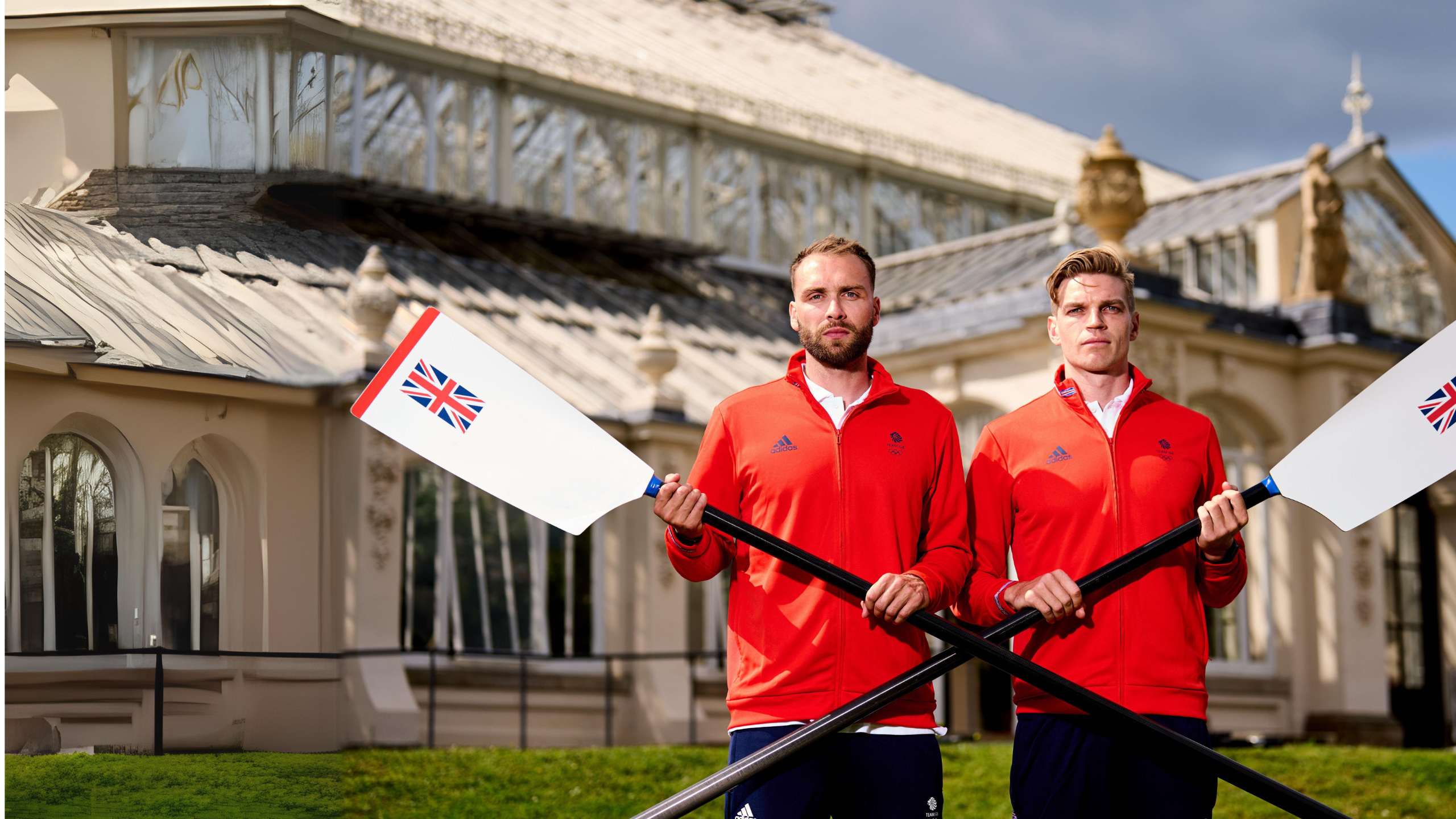 Two men with white skin and brown hair wear sports uniforms and pose with rowing oars.