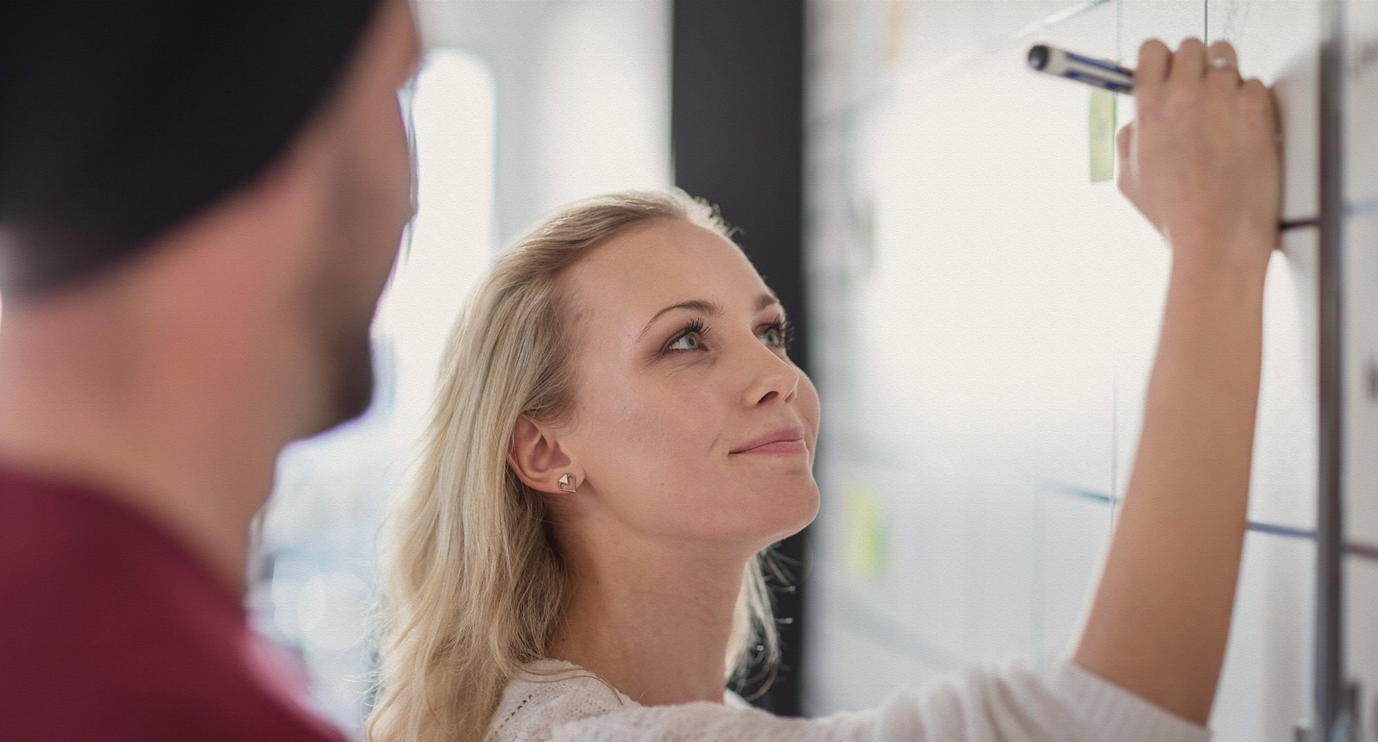 Two professionals writing on a whiteboard.