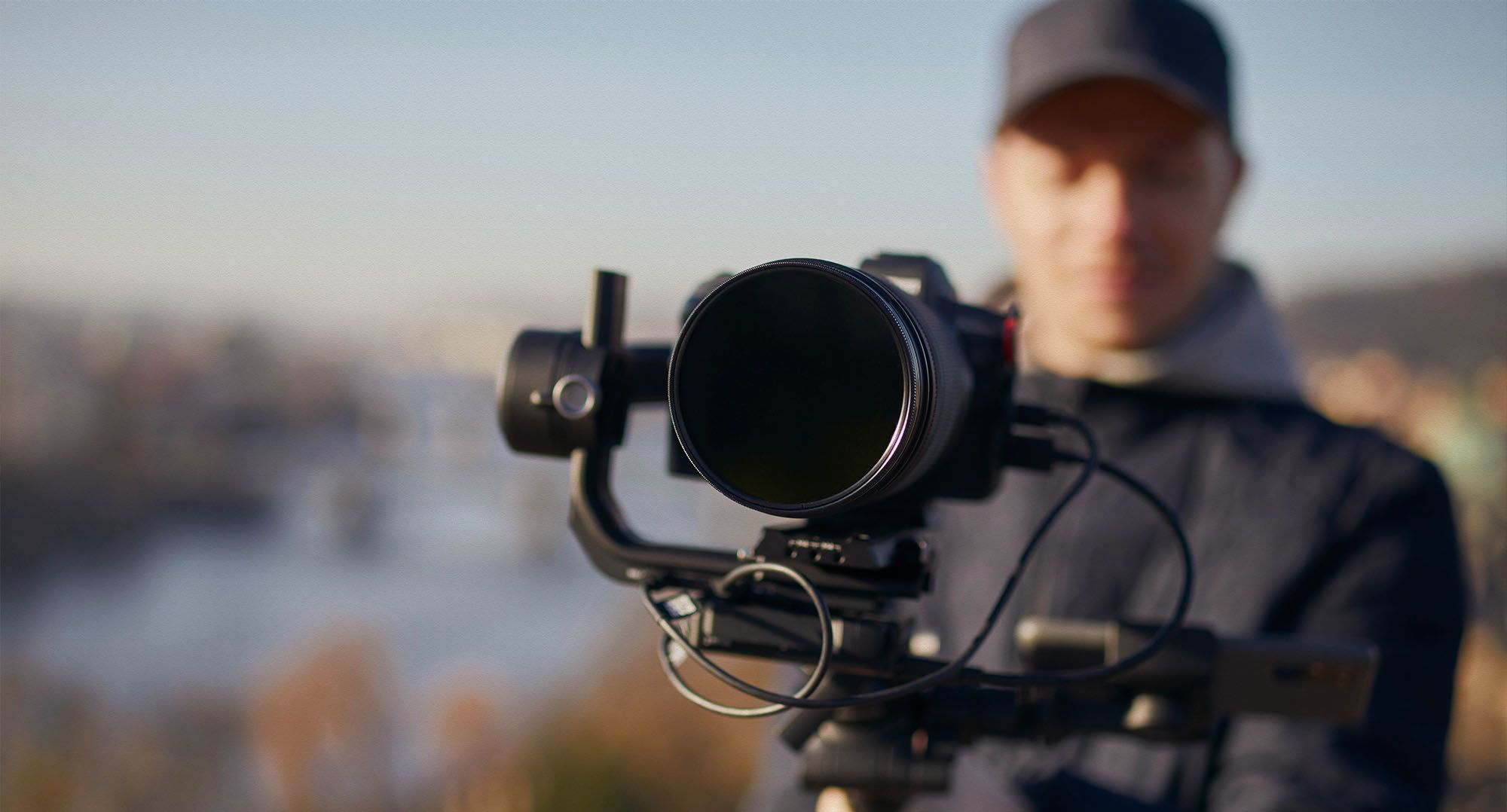 A camera operator holding a film camera outdoors.