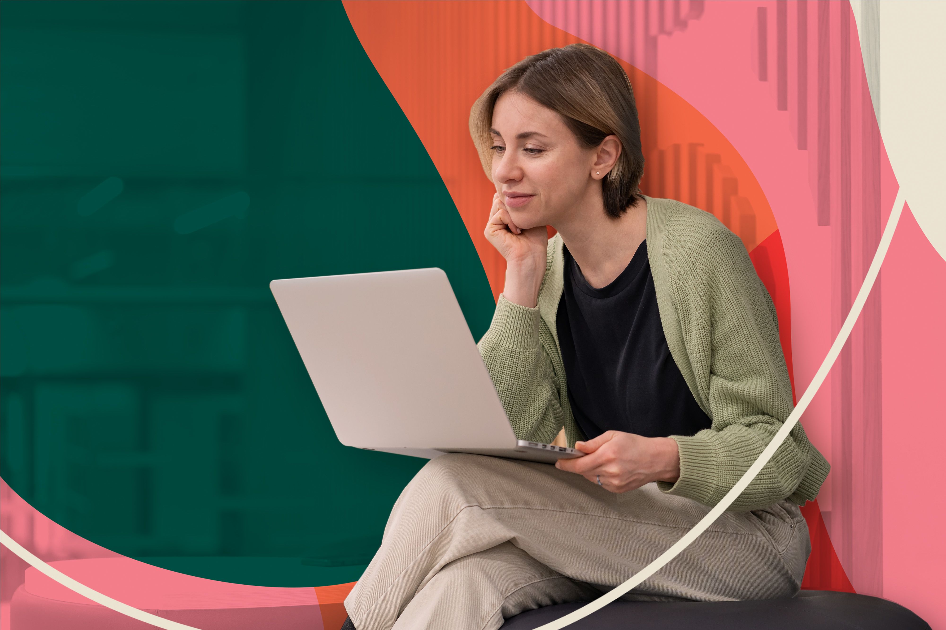 A person using a white laptop while sitting in front of a bright wall mural.