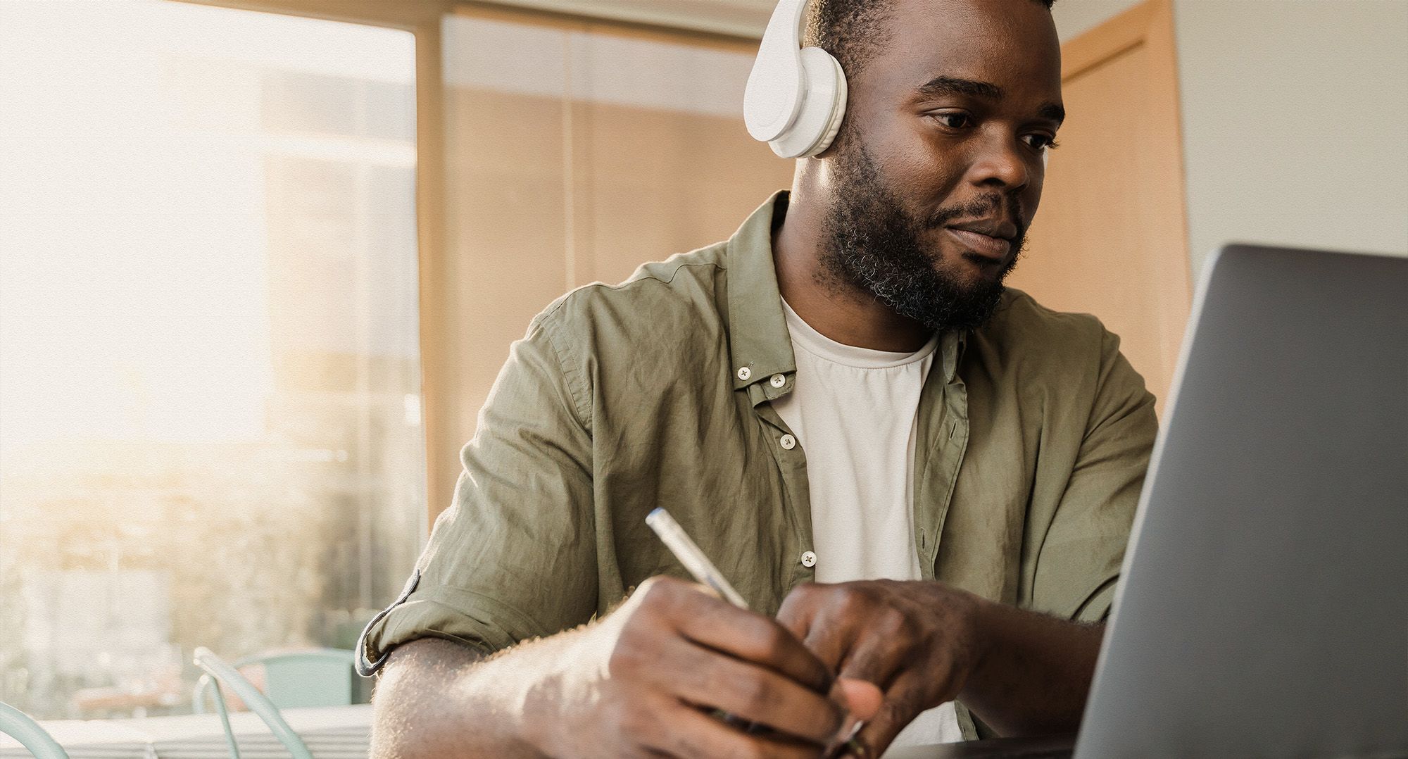 A person with headphones on working at a laptop.