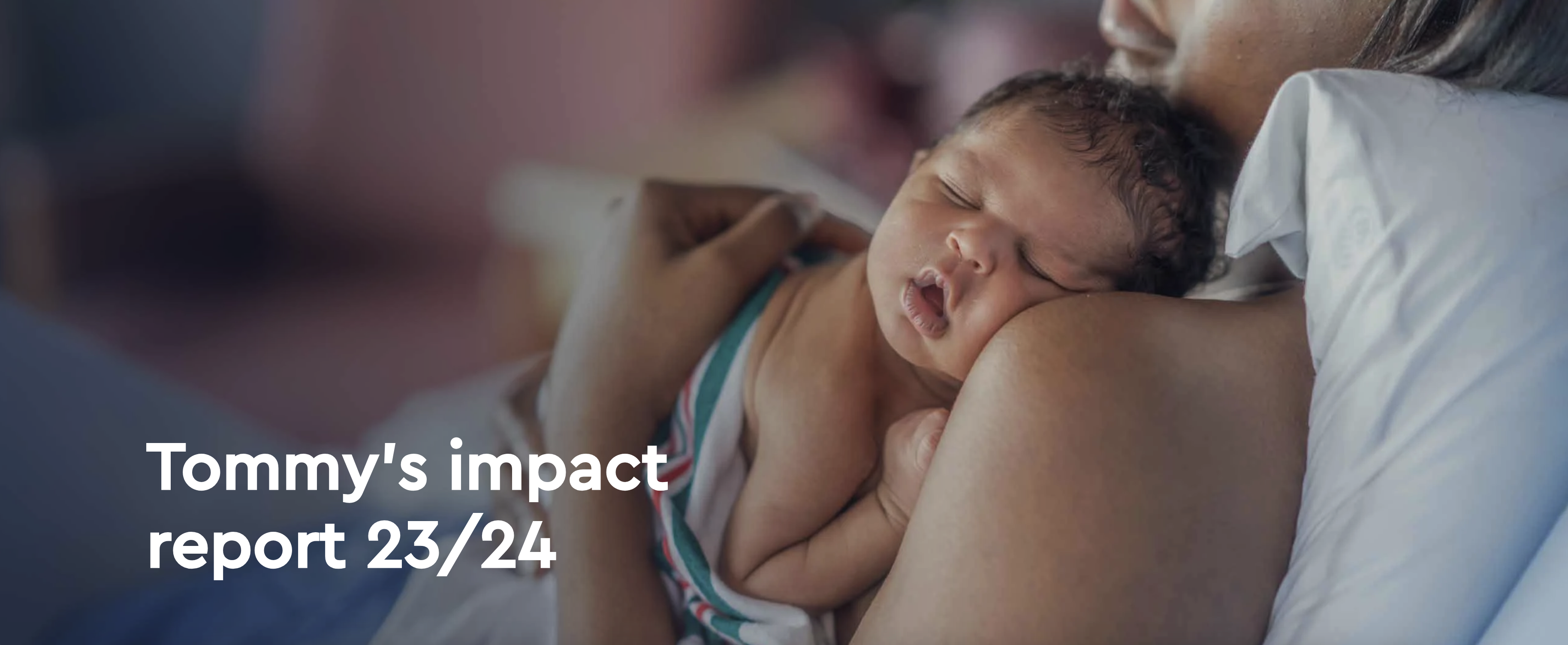 A newborn baby with dark skin and black hair sleeps on its mothers shoulder.