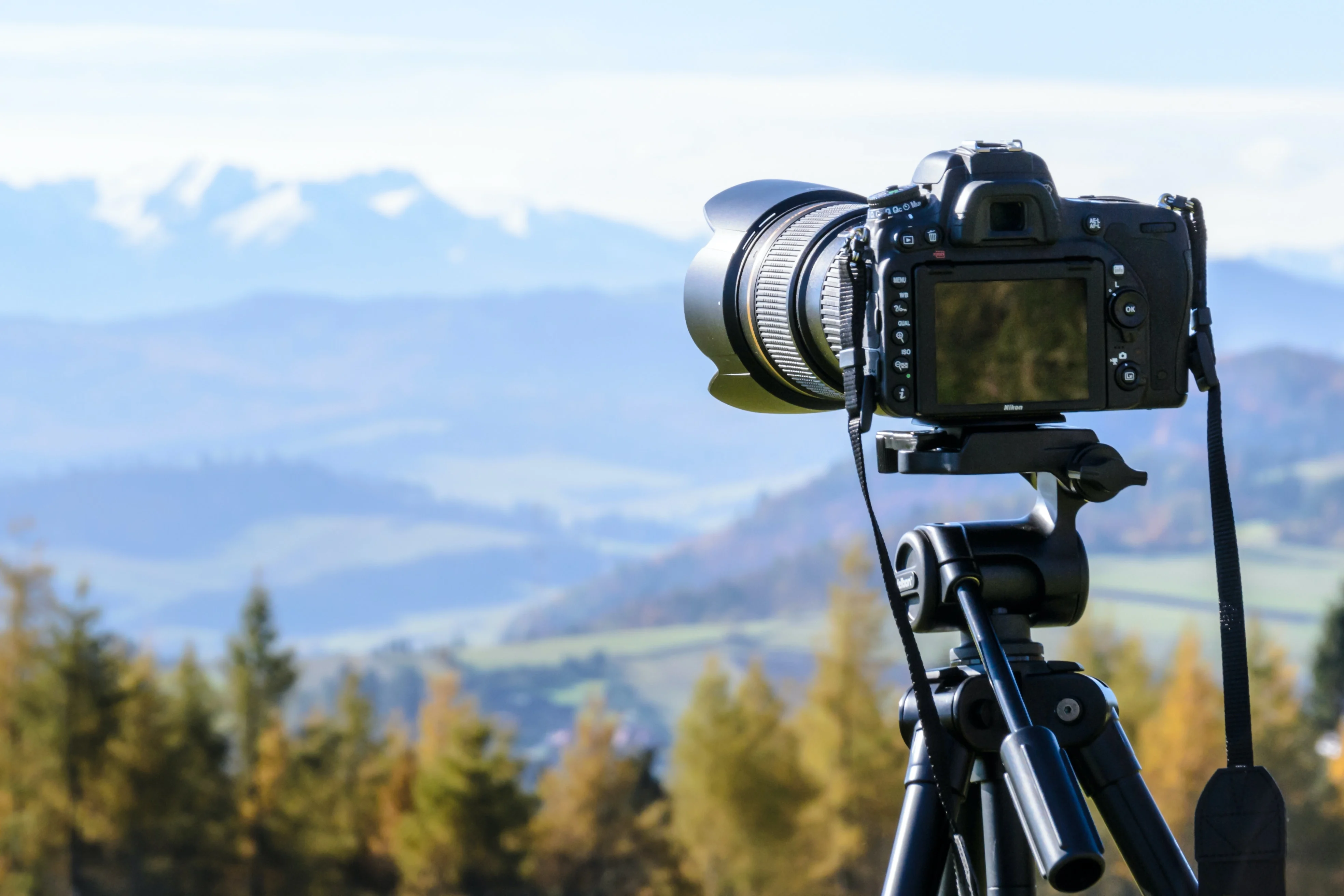 Camera sitting on a tripod, overlooking a mountain scene