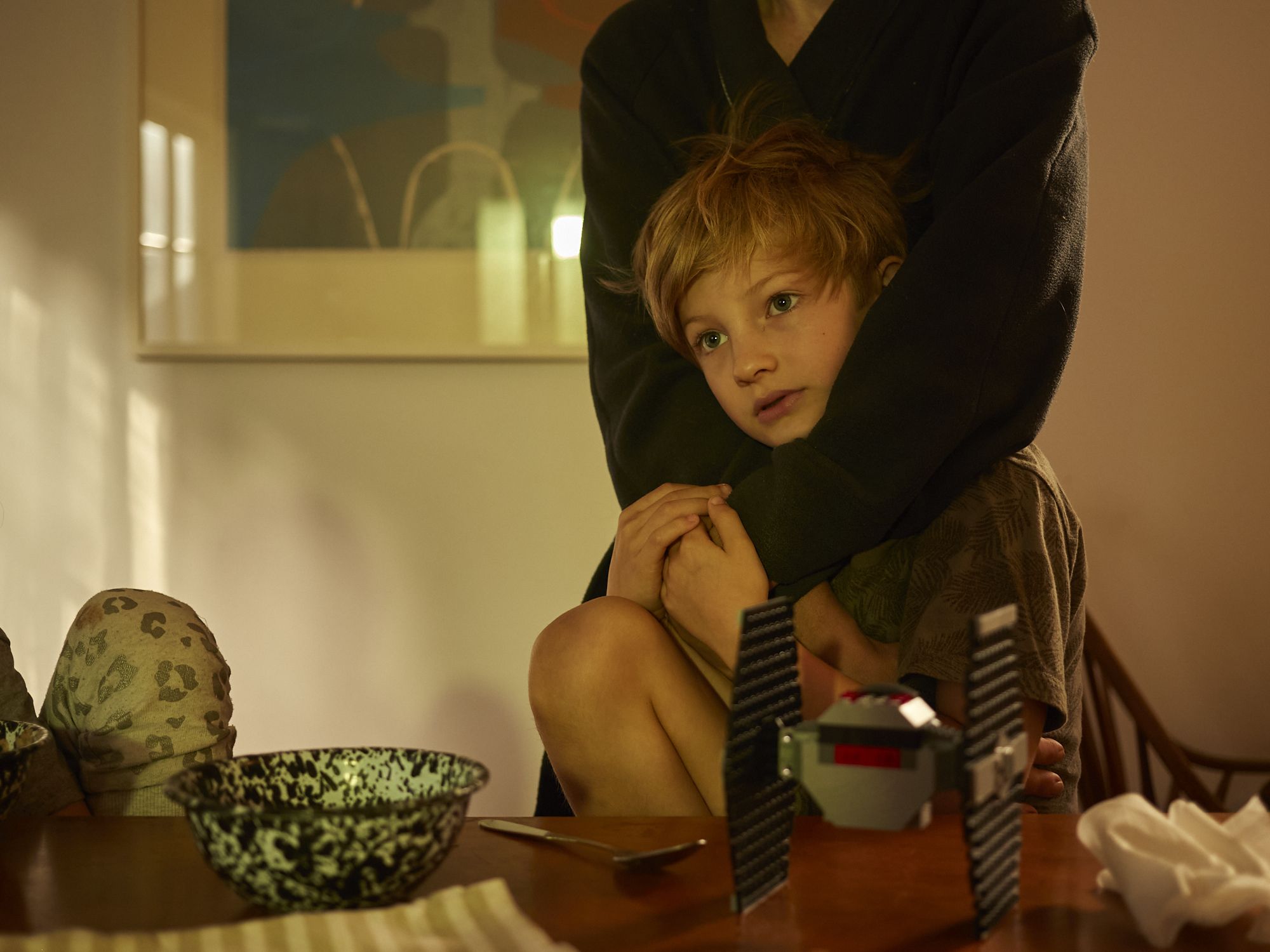 An image of a young kid being hugged by another kid.