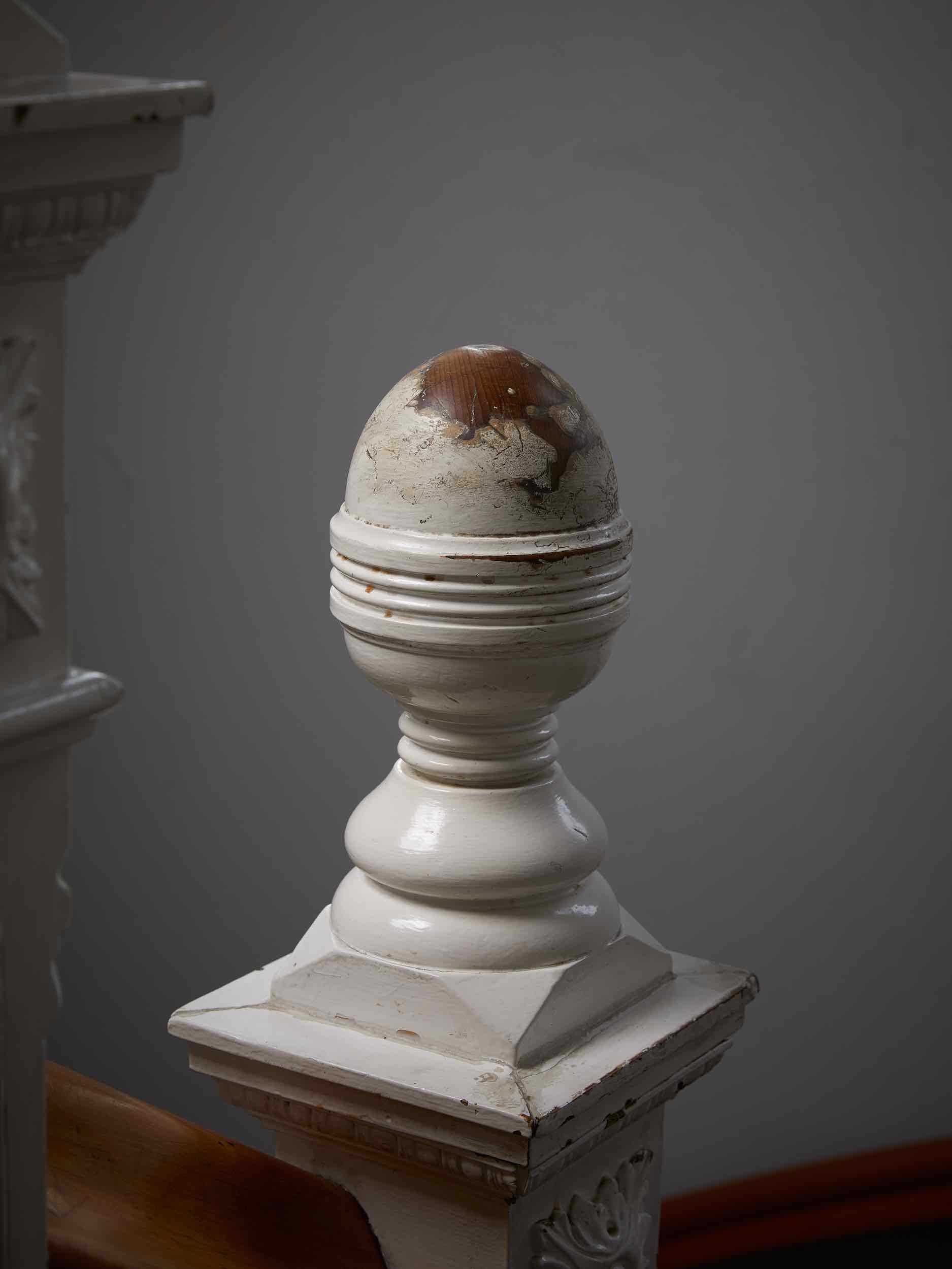 A post at the end of a staircase where paint has been removed.