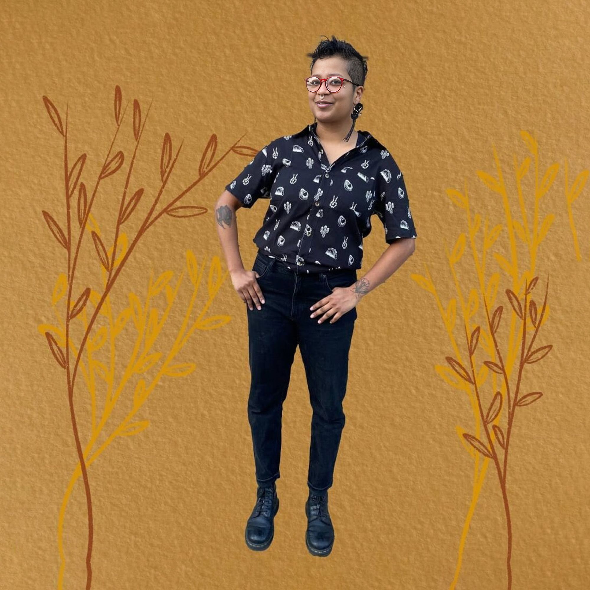 A Brown person whose hair is shaved at the sides and longer on top wears a black collared shirt. They stand in front of a dark mustard background. Sketches of barley-like plants are drawn on either side of the person in darker and lighter shades of mustard. The shirt has white stencils of different foods on it, and the person has their thumbs in the pockets of their black jeans. They smile with their head tilted forward, wearing long black earrings, a septum piercing, and round red glasses.