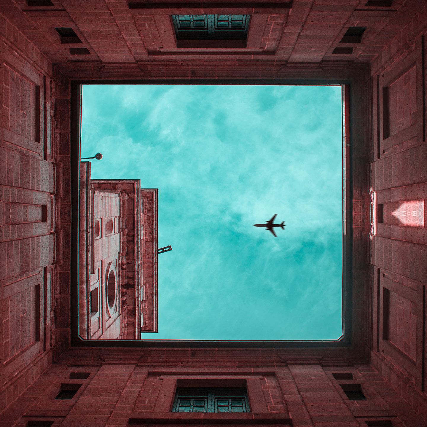 Plane in flight, framed by a square arrangement of buildings