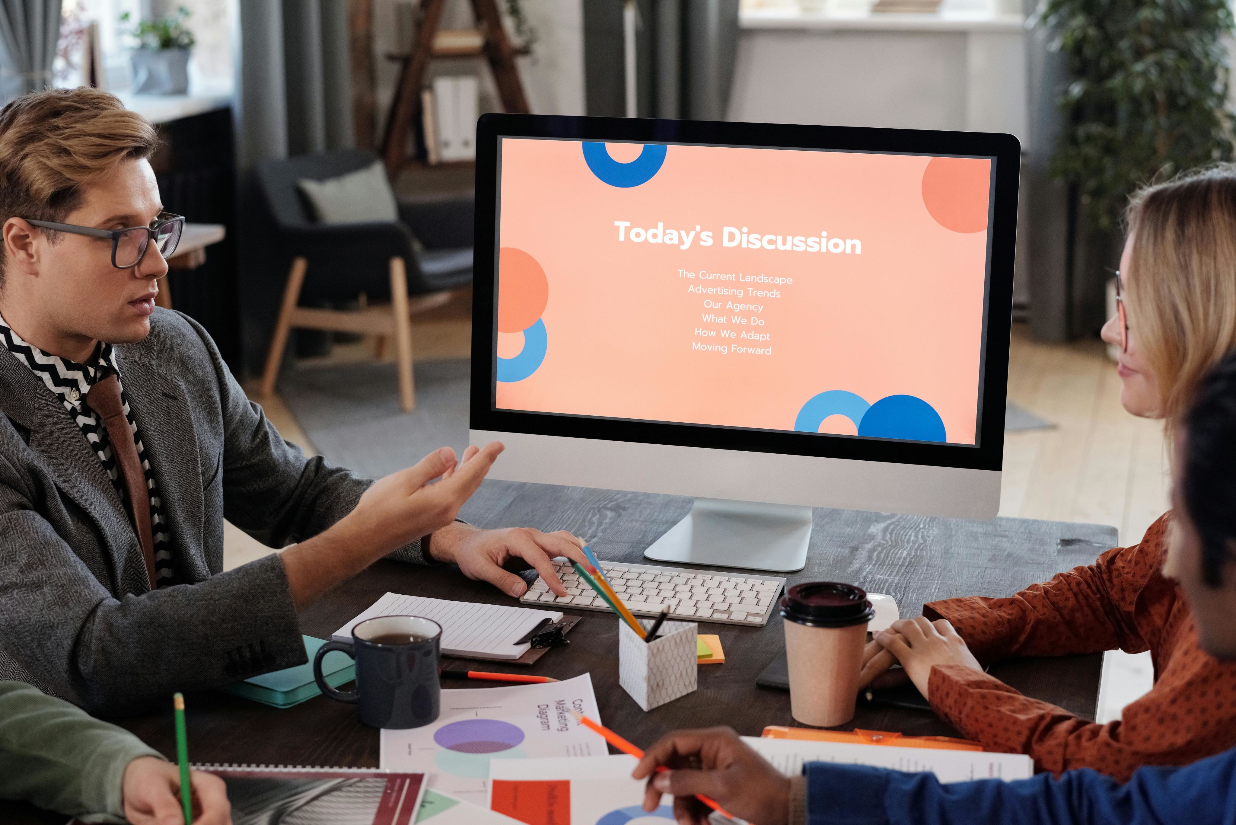 Team engaged in a productive office meeting in front of a monitor with the text 'today's discussion'