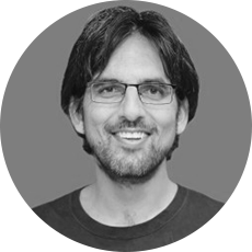 Headshot of a man with glasses, long black hair, and a beard.