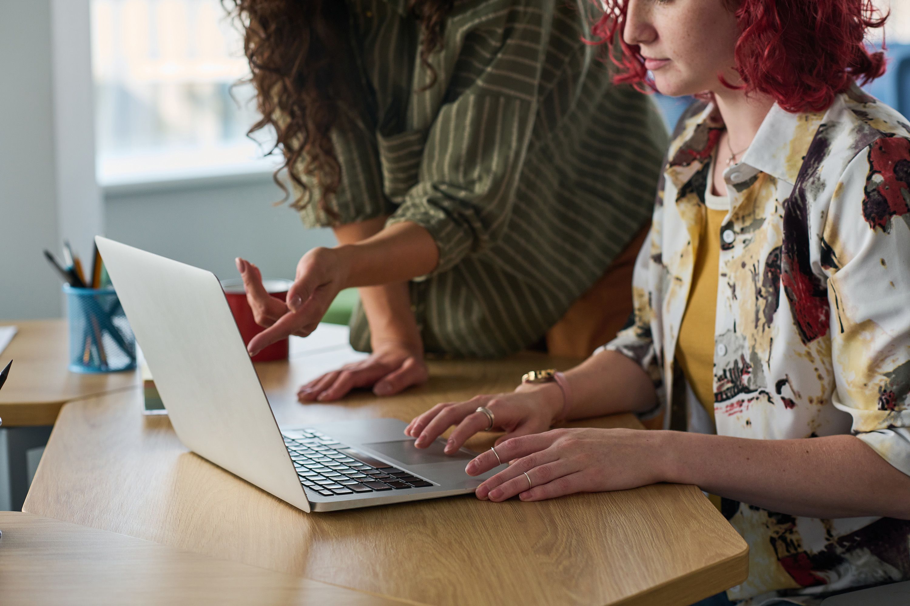 Two people sitting at a desk and working on a laptop.